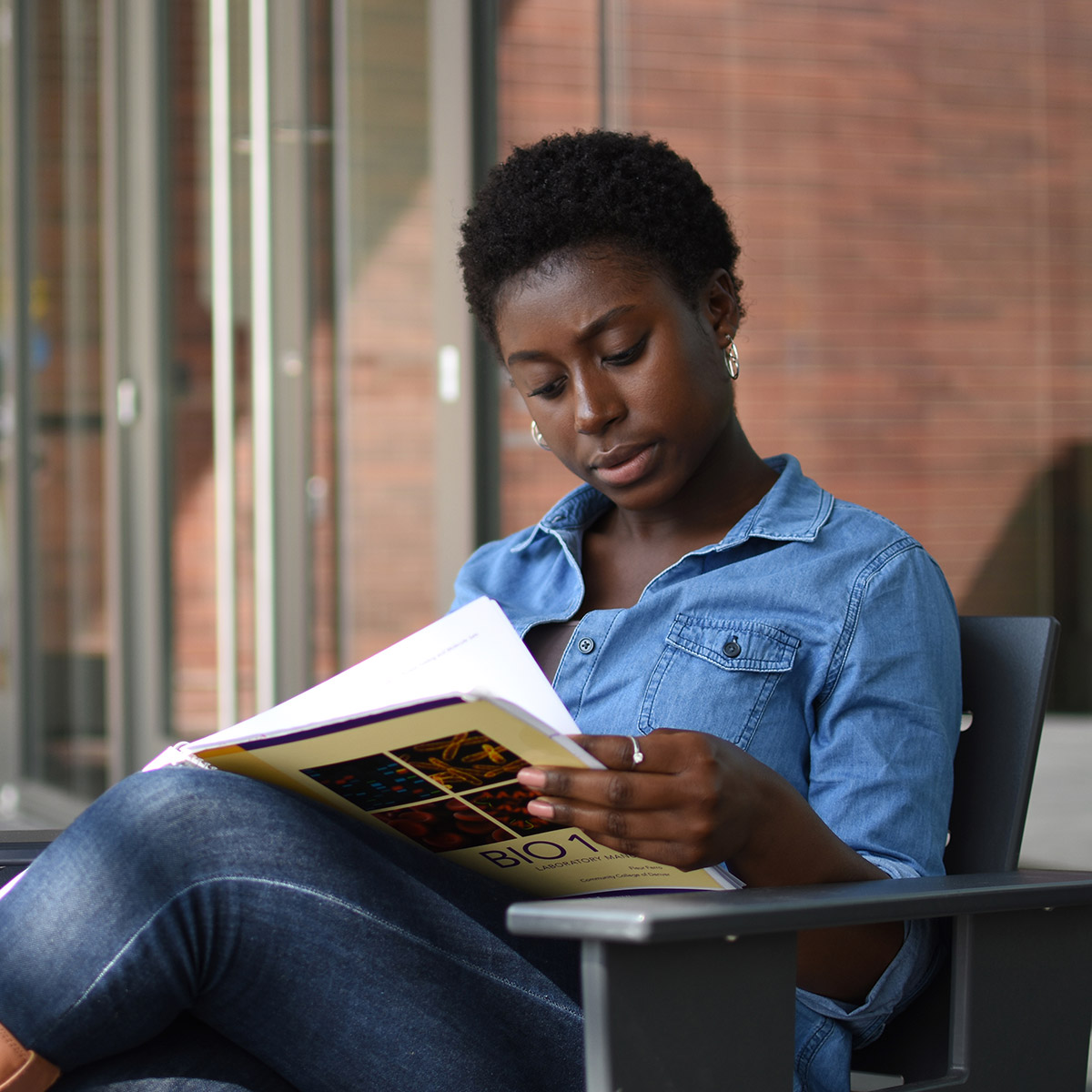 female 英雄联盟博彩竞猜 student reading a biology textbook