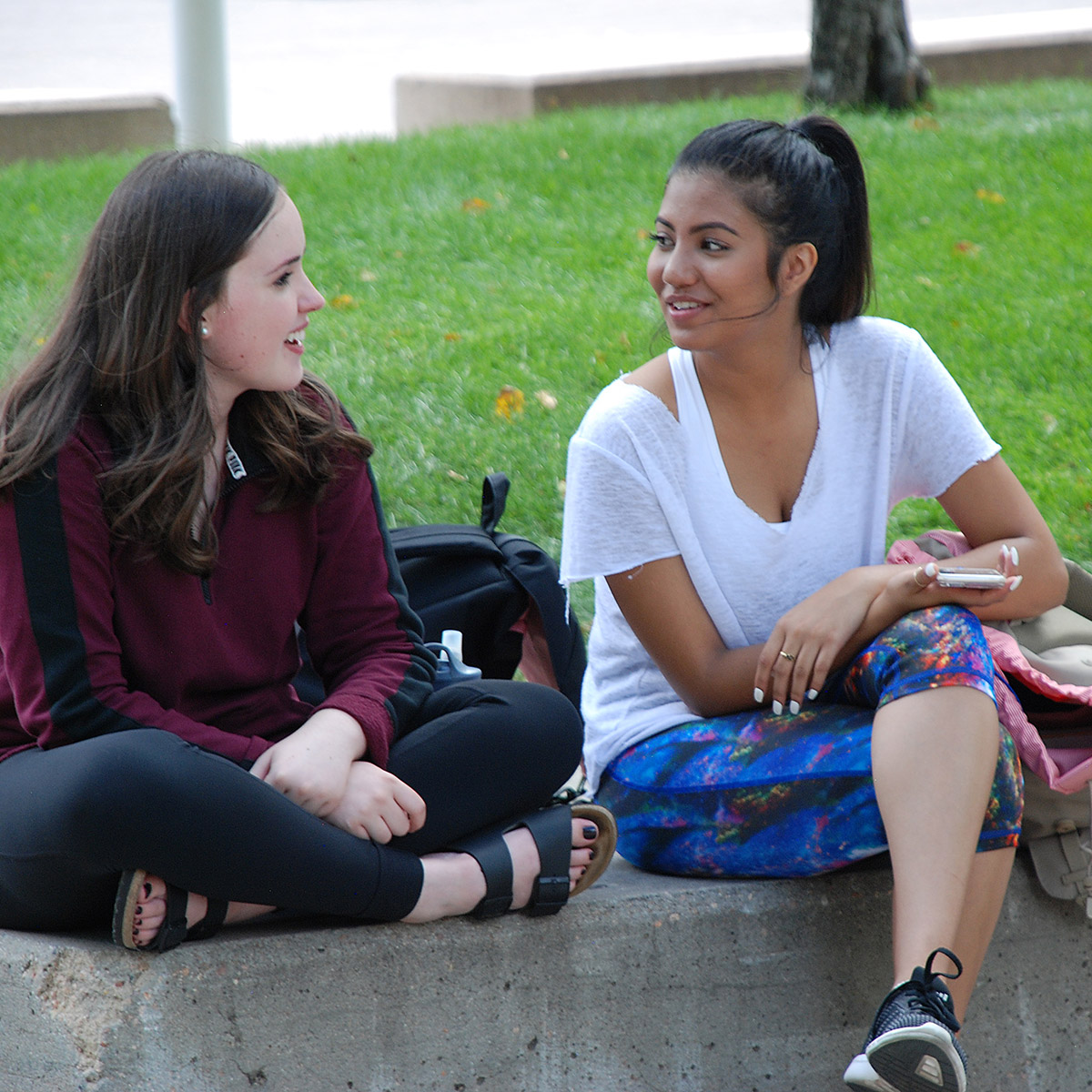 2 female 英雄联盟博彩竞猜 students sitting outside