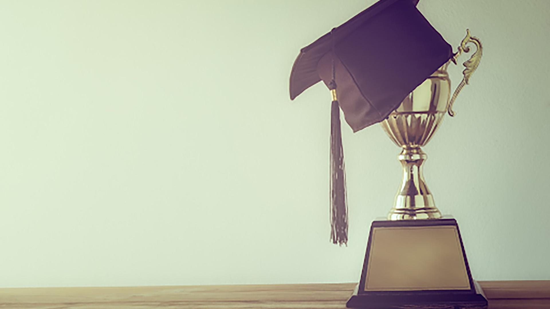 image of trophy with a graduation cap and sunset 