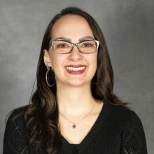 woman with long dark hair wearing glasses and a black v-neck top