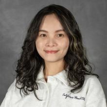 Woman with dark wavy shoulder length hair wearing a white top